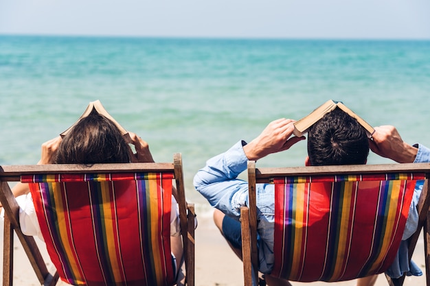 Romantisches liebendes junges Paar entspannend, das zusammen am tropischen Strand sitzt und auf das Meer schaut. Sommerferien