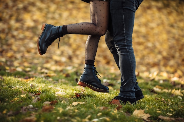 Romantisches Liebeskonzept. Füße eines verliebten jungen Paares im Herbstpark. Sanfter Kuss des jungen Paares.