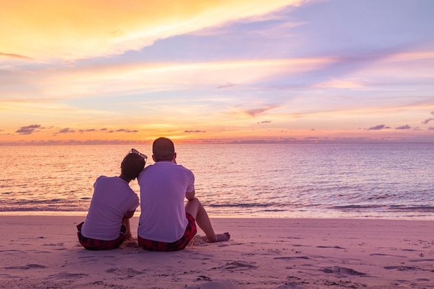 Romantisches Liebespaar am Strand bei farbenprächtigem Sonnenuntergang im Hintergrund Ruhige tropische Sonnenuntergangslandschaft