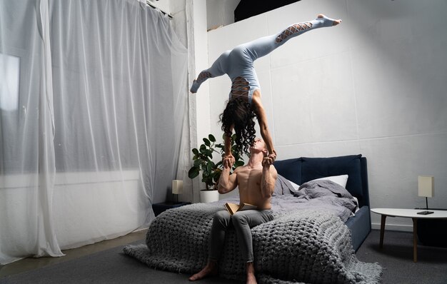 Romantisches Paar, das akrobatischen Trick im Schlafzimmer macht.