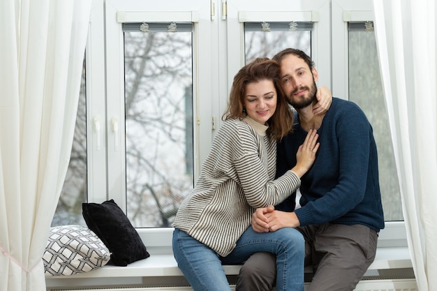 Romantisches Paar, das aus dem Fenster schaut. Quarantäne zu Hause.