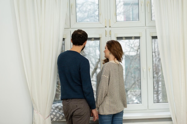 Romantisches Paar, das aus dem Fenster schaut. Quarantäne zu Hause.