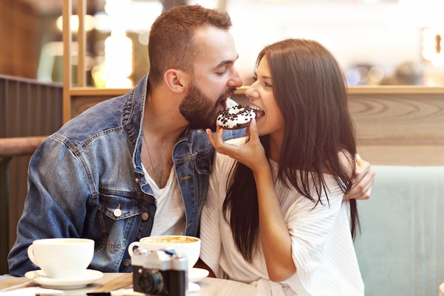 Romantisches Paar, das im Café verabredet und Donut isst