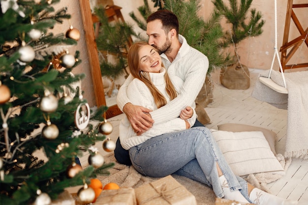 Romantisches Paar, das zu Hause auf einem Boden in der Nähe des Weihnachtsbaums sitzt