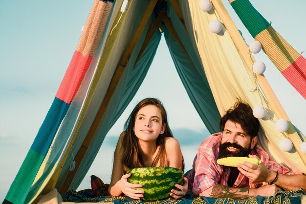 Romantisches Paar isst Wassermelone im Zeltcamping auf Naturhintergrund Abenteuer für junge Freunde am Sommertag