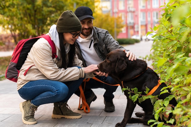 Romantisches Paar ist mit ihrem Hund Labrador auf einem Spaziergang in der Stadt. Schöne junge Frau und gutaussehender Mann haben Spaß im Freien mit braunem Hündchen