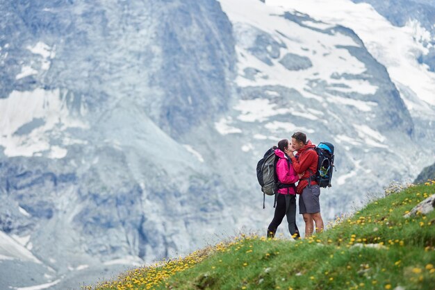 Romantisches Paar küsst sich auf einer grünen Wiese vor felsigem Hintergrund der Schweizer Alpen