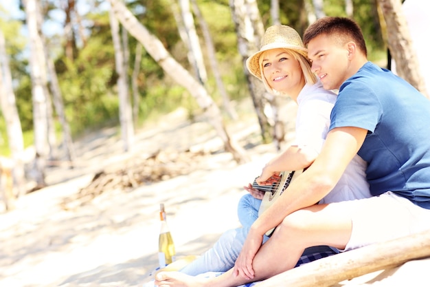 romantisches Paar spielt Gitarre am Strand