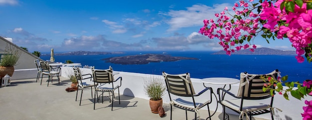 Romantisches Paar Tische aus weißem Marmor im Freien, Stühle auf der Terrasse mit Blumen und Blick auf das Meer, Oia