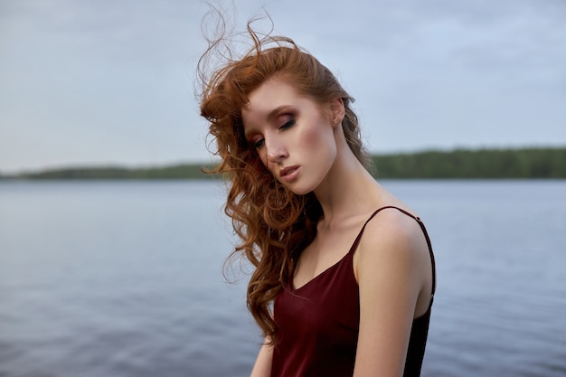 Romantisches Porträt der Schönheit der jungen rothaarigen Frau nahe Teich. Schönes Make-up, Mädchen ruht und entspannt