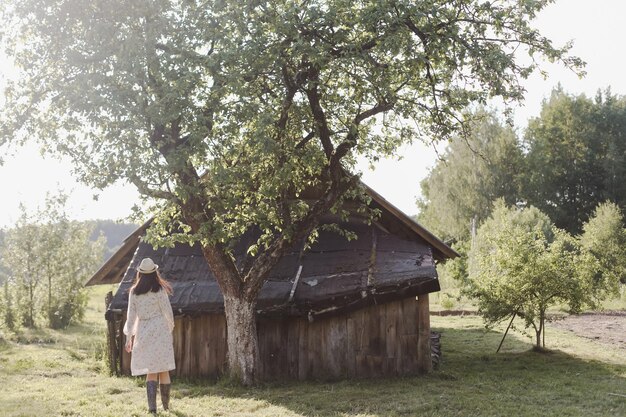 Romantisches Porträt einer jungen Frau mit Strohhut und schönem Kleid auf dem Land im Sommer