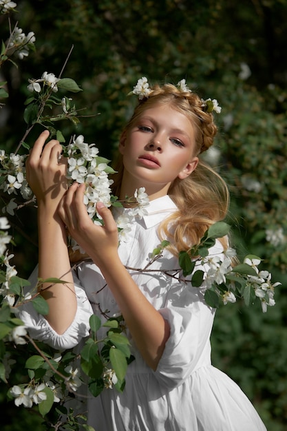 Romantisches Porträt eines Mädchens im Park nahe einem blühenden Apfelbaum. Naturkosmetik. Natürliche Schönheit einer Frau in einem weißen Kleid