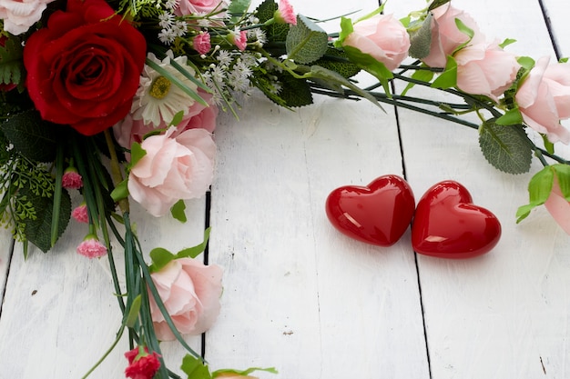 Romantisches rotes Herz des Valentinstags und bunter Blumenstrauß auf weißem Holztisch