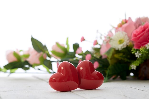 Romantisches rotes Herz des Valentinstags und bunter Blumenstrauß auf weißem Holztisch