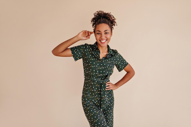 Romantisches schwarzes Mädchen, das mit der Hand auf der Hüfte posiert Studioaufnahme einer glamourösen afroamerikanischen Frau in grünen Overalls