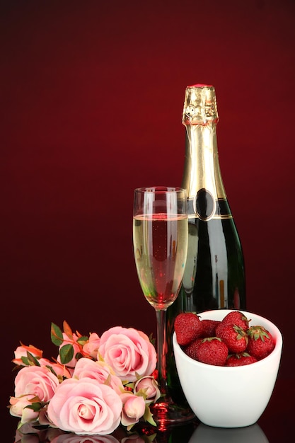 Romantisches Stillleben mit Champagner, Erdbeere und rosa Rosen auf dunklem Hintergrund