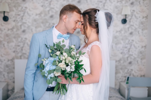 Romantisches Treffen der Braut und des Bräutigams im Hotelzimmer Die Braut hält einen Hochzeitsstrauß aus weißen Rosen und Hortensien am Morgen vor der Hochzeit