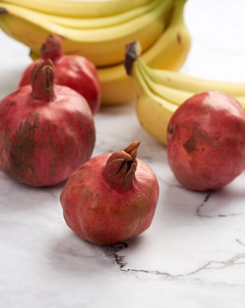 Romãs maduras e bananas na mesa de mármore