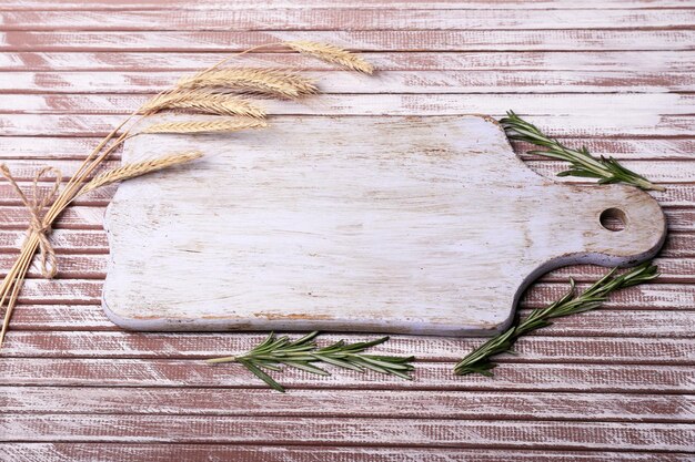Romero de orejas de trigo y tabla de cortar en mesa de madera