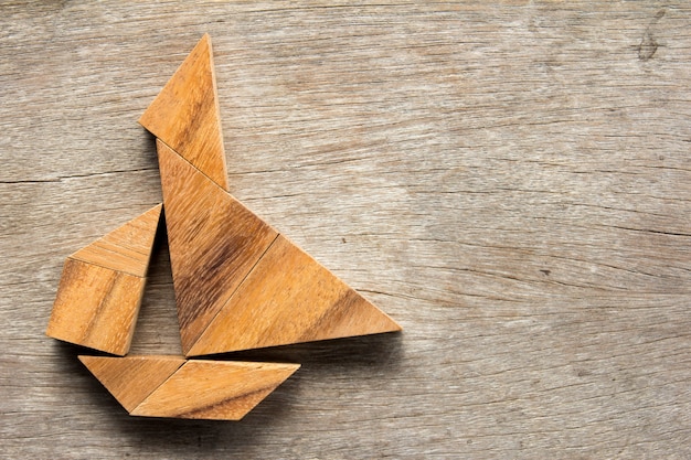 Rompecabezas chino del tangram en forma del barco de vela en fondo de madera