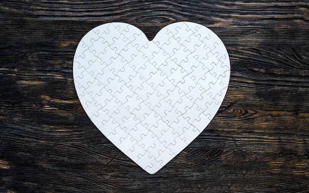 Rompecabezas de forma de corazón blanco sobre mesa negra como símbolo de amor romántico y sentimientos