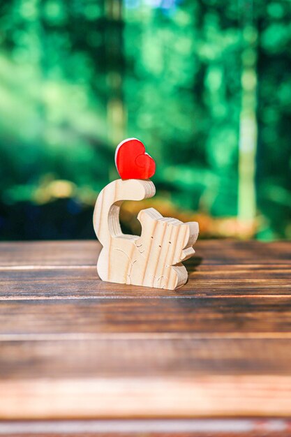 Rompecabezas de madera borrosa en forma de un gato hecho a mano con un corazón en el fondo de un bosque borroso