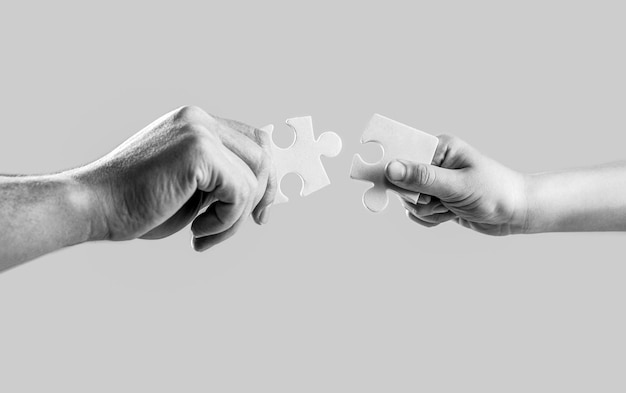 Rompecabezas de primer plano Manos sosteniendo rompecabezas Hombres y niños manos conectando rompecabeos en blanco y negro