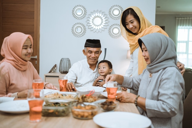 Rompiendo el ayuno. Asiático musulmán con hijab cenando juntos en casa iftar sentados en la mesa de comedor