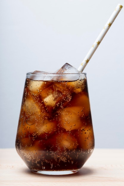 Ron con cola y hielo en un vaso de primer plano cola con hielo bebida de verano