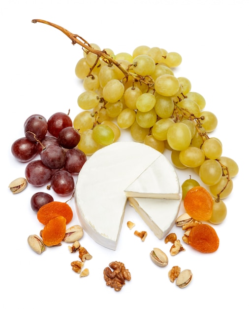 Ronda de queso brie o camembert y uvas en una mesa blanca