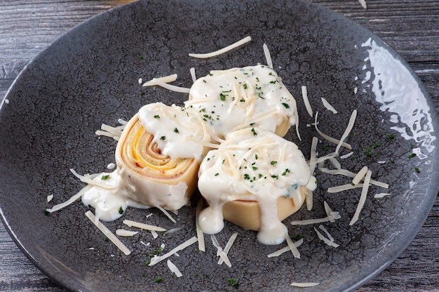 Rondelli de presunto e queijo coberto com molho de parmesão branco