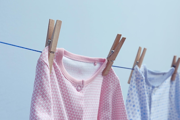 Ropa de bebé colgando de una cuerda sobre fondo gris