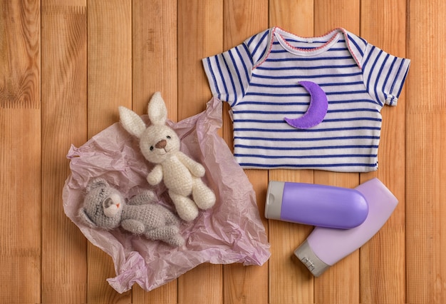 Ropa de bebé, juguetes y cosméticos en mesa de madera, endecha plana