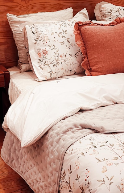 Ropa de cama de estilo rural vintage con motivos florales en la cama de madera en el diseño interior del dormitorio