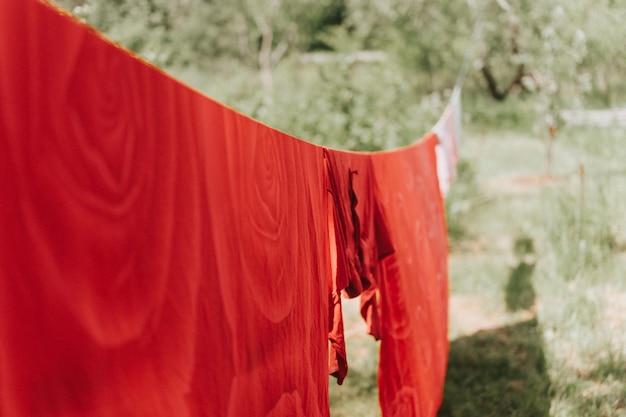 La ropa de cama roja se seca en un tendedero en la calle, en el patio de la casa de campo de la aldea, la frescura del verano y la tarea del día de la lavandería y la tarea de colgar la ropa para que se seque en una cuerda