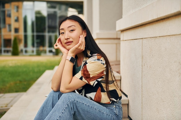 En ropa casual, la joven asiática está al aire libre durante el día