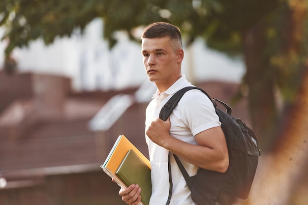 Con ropa casual, un joven estudiante está al aire libre.