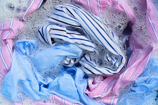 La ropa de color se remoja en detergente en polvo, disolución de agua. Concepto de lavandería