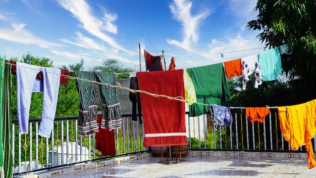 Ropa colorida colgada para secarse en un tendedero y sol brillando en el cielo azul