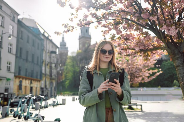 Ropa elegante chica rubia turista viaja buscando direcciones en el teléfono inteligente mientras viaja a través