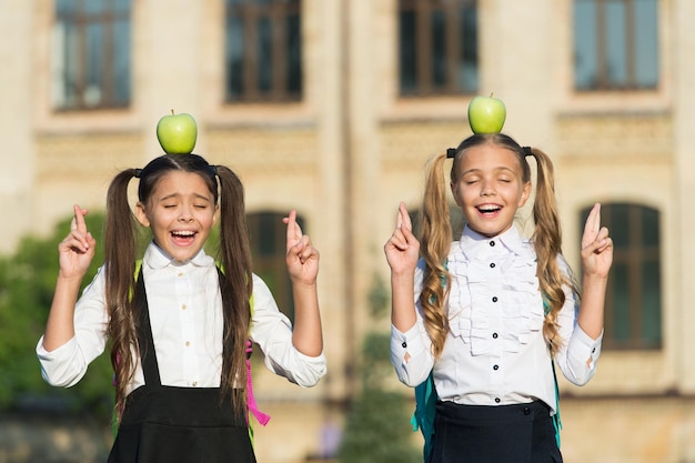 Ropa de escuela de niñas sonrientes con manzanas en la parte superior de la cabeza Esperanza para el mejor concepto