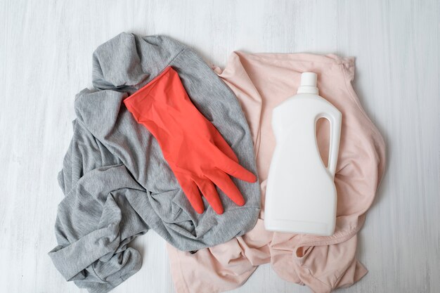 Ropa, guantes de goma y botella con detergente. Vista superior