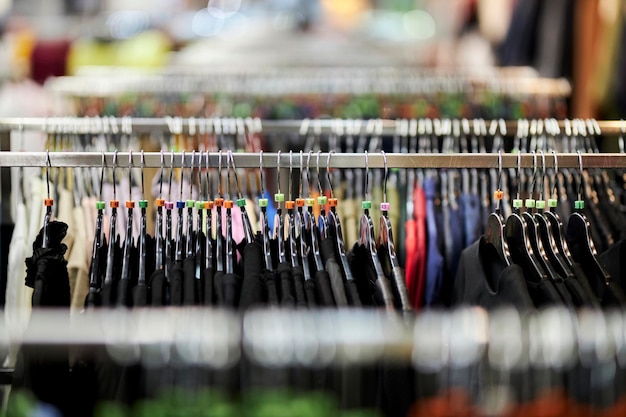 ropa de hombre: camisetas coloridas, sudaderas con capucha y sudaderas en una percha en una tienda de ropa