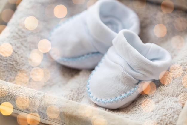 ropa, infancia, maternidad y concepto de objeto - cierre de patucos de bebé blancos para niño recién nacido en toalla en cesta