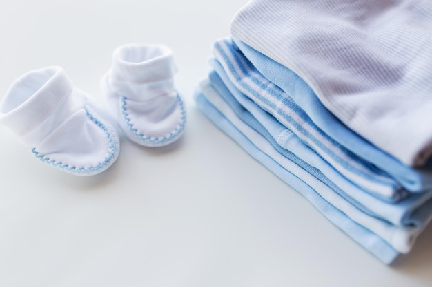 ropa, infancia, maternidad y concepto de objeto - cierre de patucos de bebé en un montón de ropa doblada para niño recién nacido