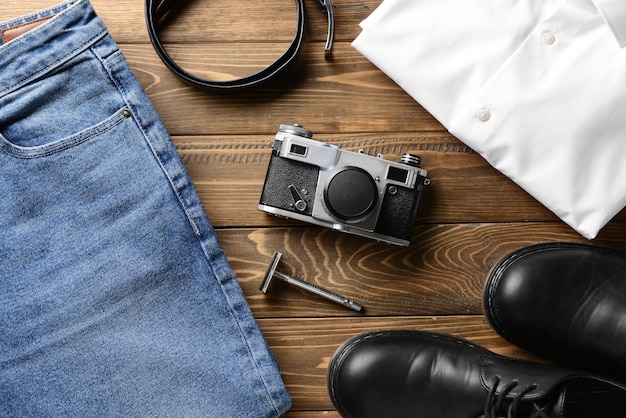 Ropa masculina elegante con accesorios y cámara de fotos en mesa de madera