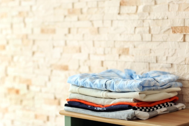 Ropa masculina tirada en la mesita de noche frente al fondo de la pared de ladrillo