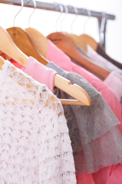 Ropa de mujer gris y rosa en perchas de madera sobre un fondo blanco. armario de mujer