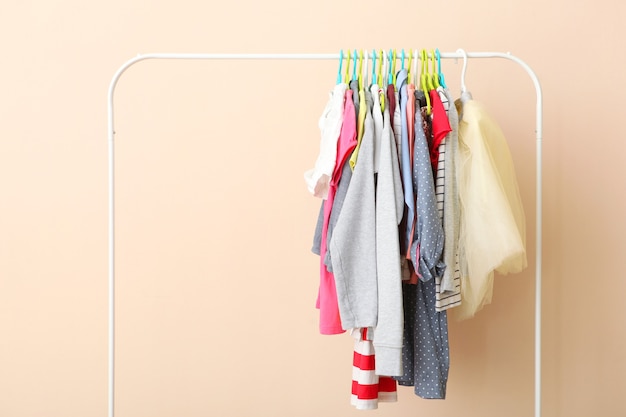 Foto ropa de niños en una percha sobre un fondo de color