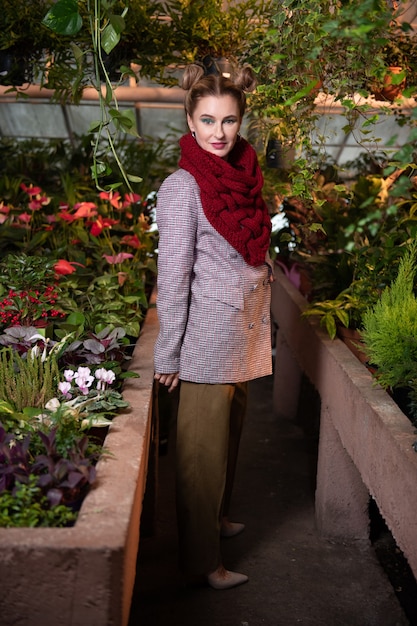 Ropa de otoño. Bonita mujer positiva con un abrigo mientras está en el invernadero